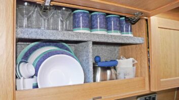 Caravan kitchen cupboards loaded with crockery and cups