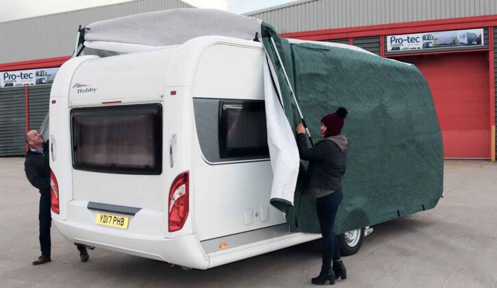 Two people fitting a caravan cover