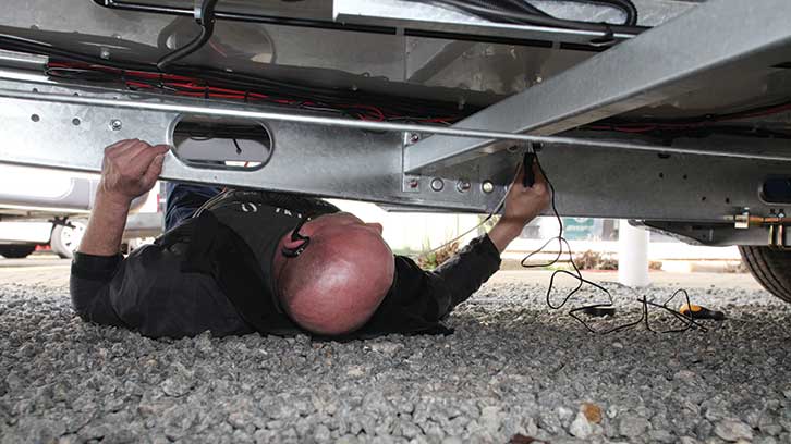 Andy underneath the caravan feeding the power cable through