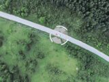 An aerial tracking shot of a car and caravan on the road