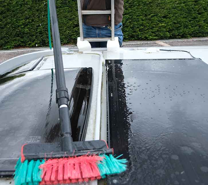 Using a long handled brush to reach the centre of the roof