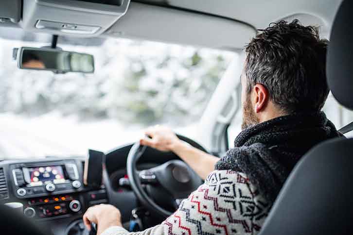 A man driving a car in wintery conditions