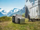 The EcoFlow Delta 3 Plus by a caravan with mountains in the background