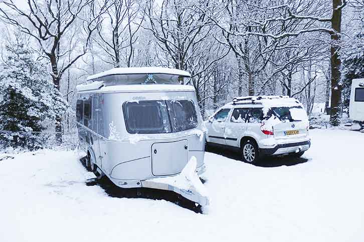 A caravan pitched up at a snowy campsite