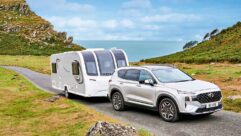 A car towing a caravan with the sea in the background