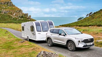 A car towing a caravan with the sea in the background