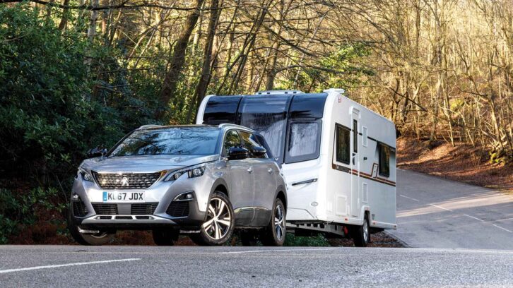 A Peugeot 5008 towing a caravan on a road