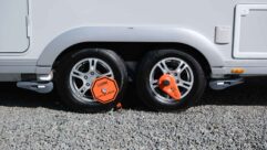 A twin axle caravan's tyres with wheel clamps in placea